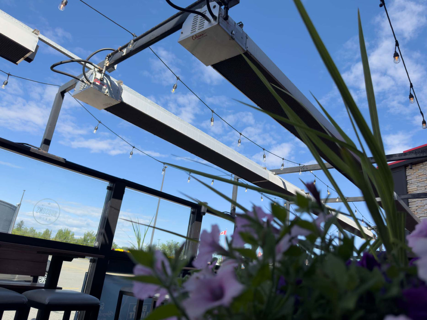 Patio heaters ceiling mounted near flowers.