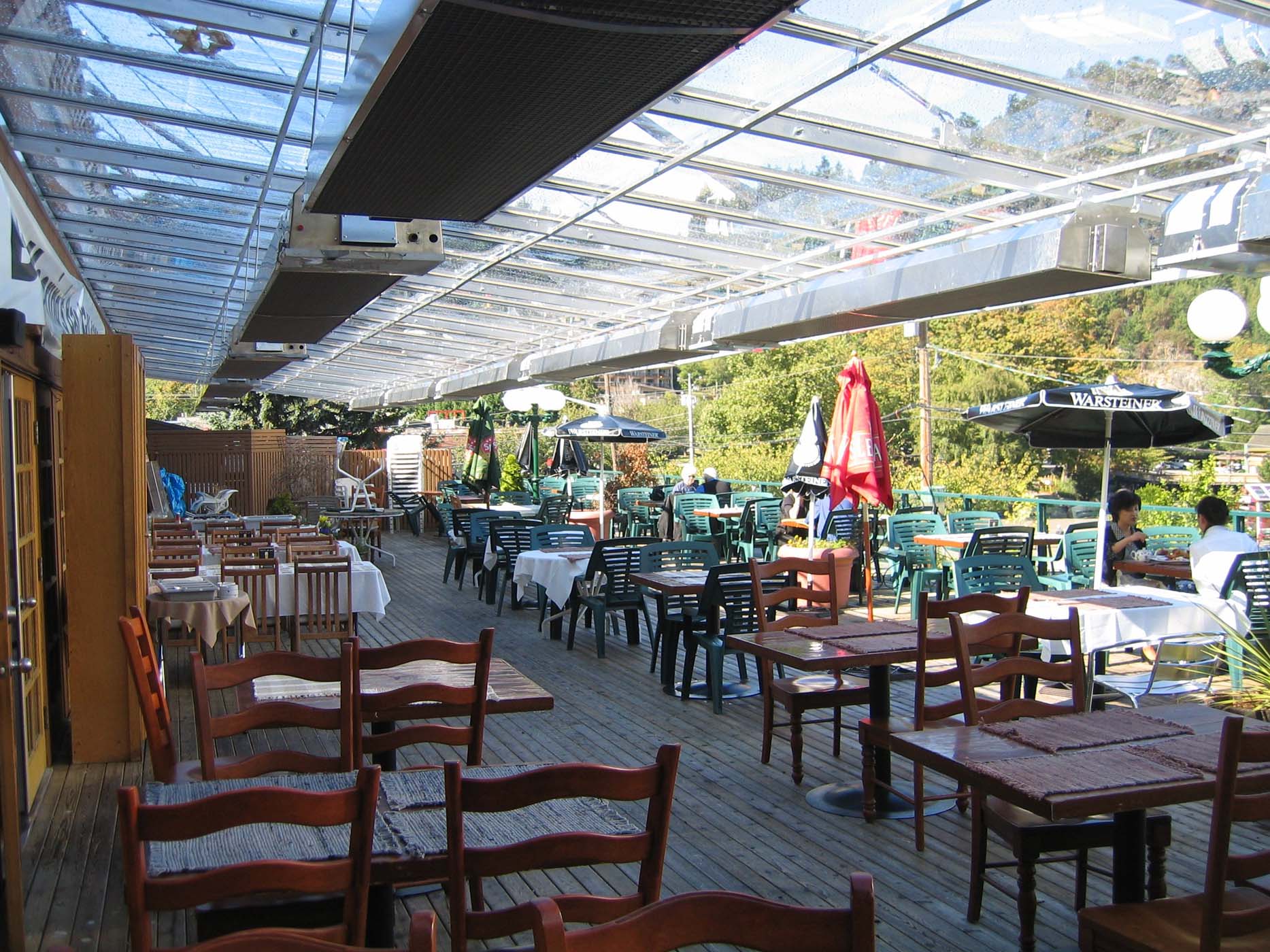 Wall-mounted infrared patio heaters warming an elegant restaurant patio filled with guests dining comfortably in cool weather