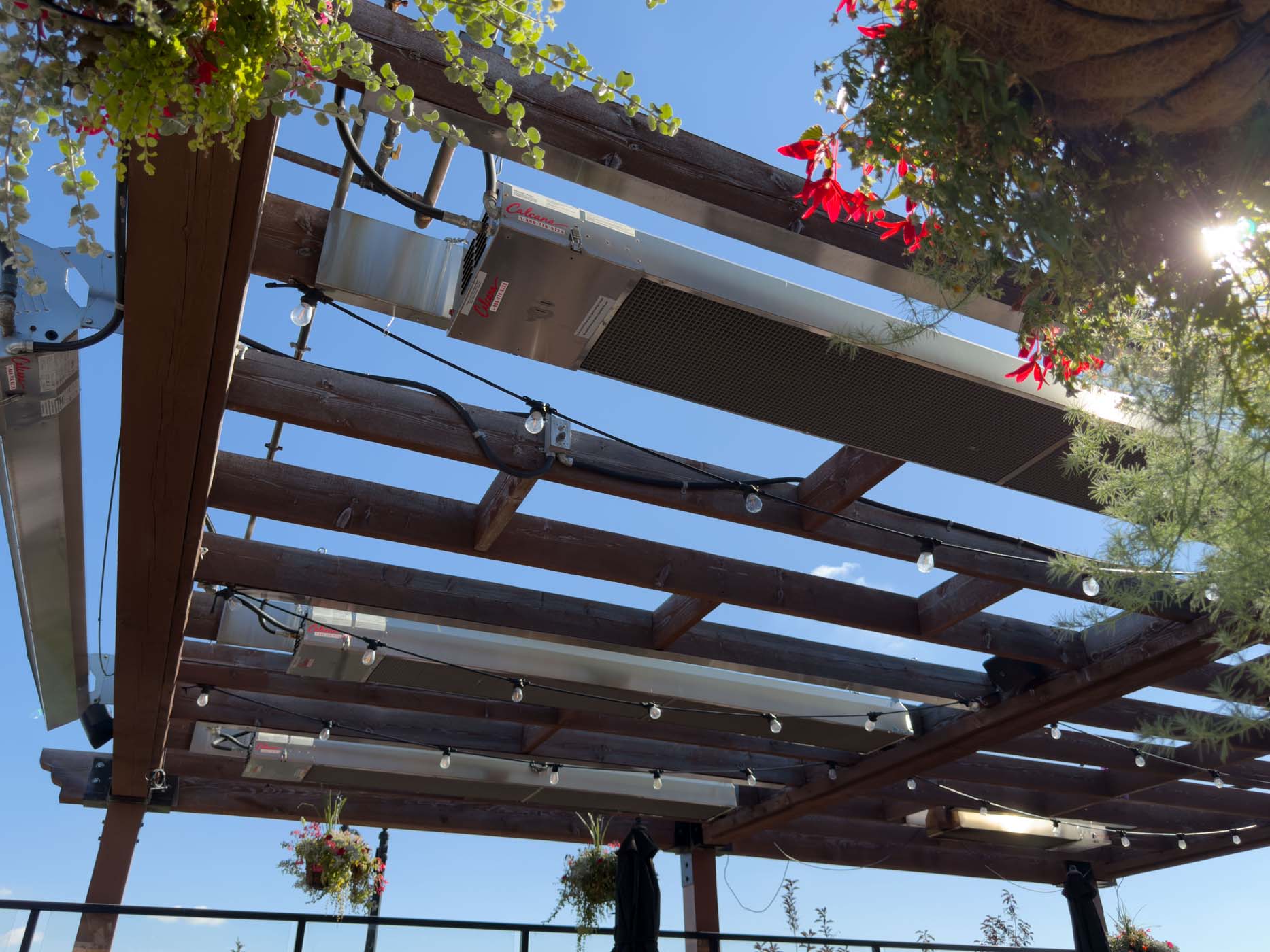Set of Calcana Infrared Heaters Warming Patio with Flowers Surrounding & Beams of Sunlight at Brewsters Calgary