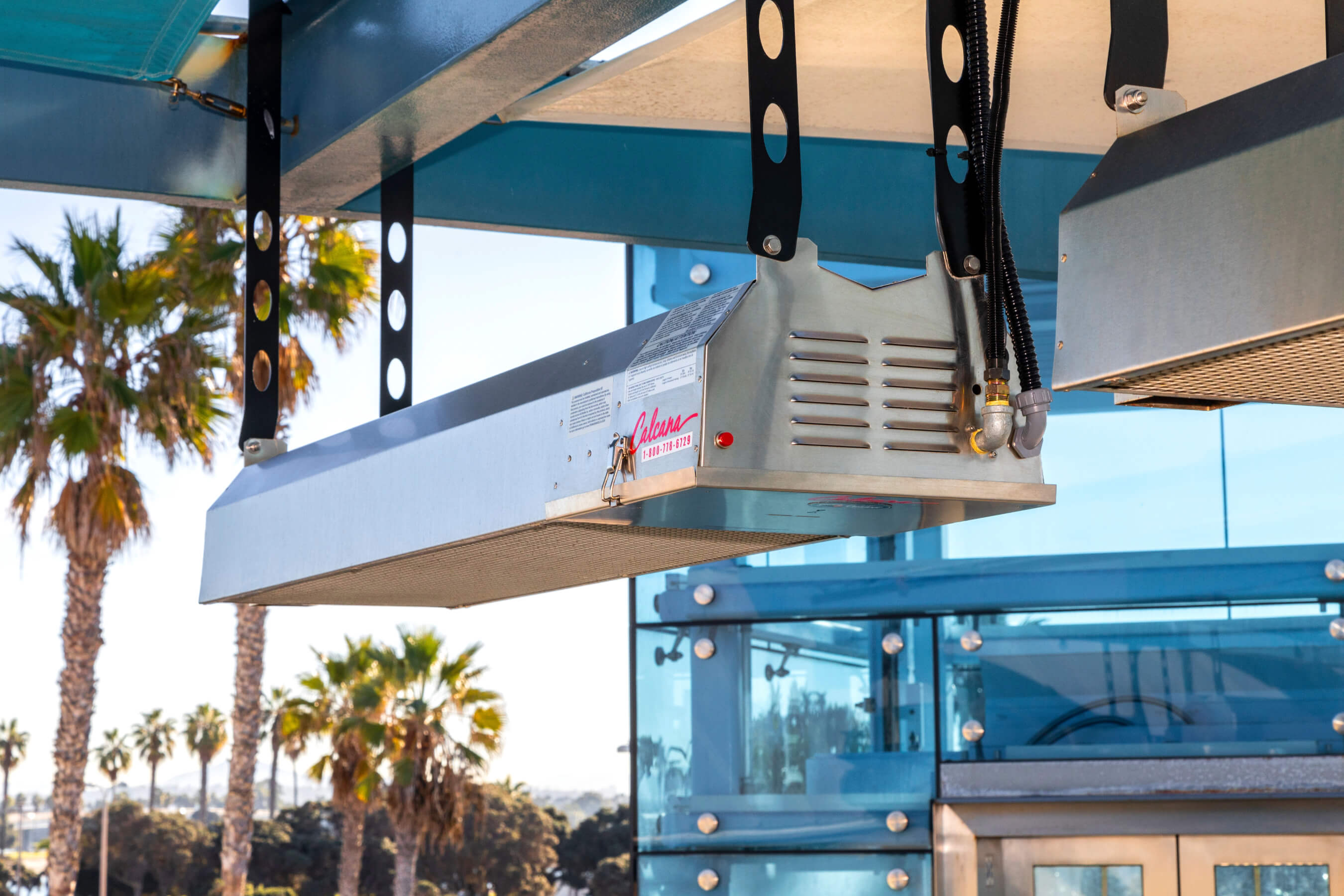 Infrared Patio Heater hanging with palm trees in the background.