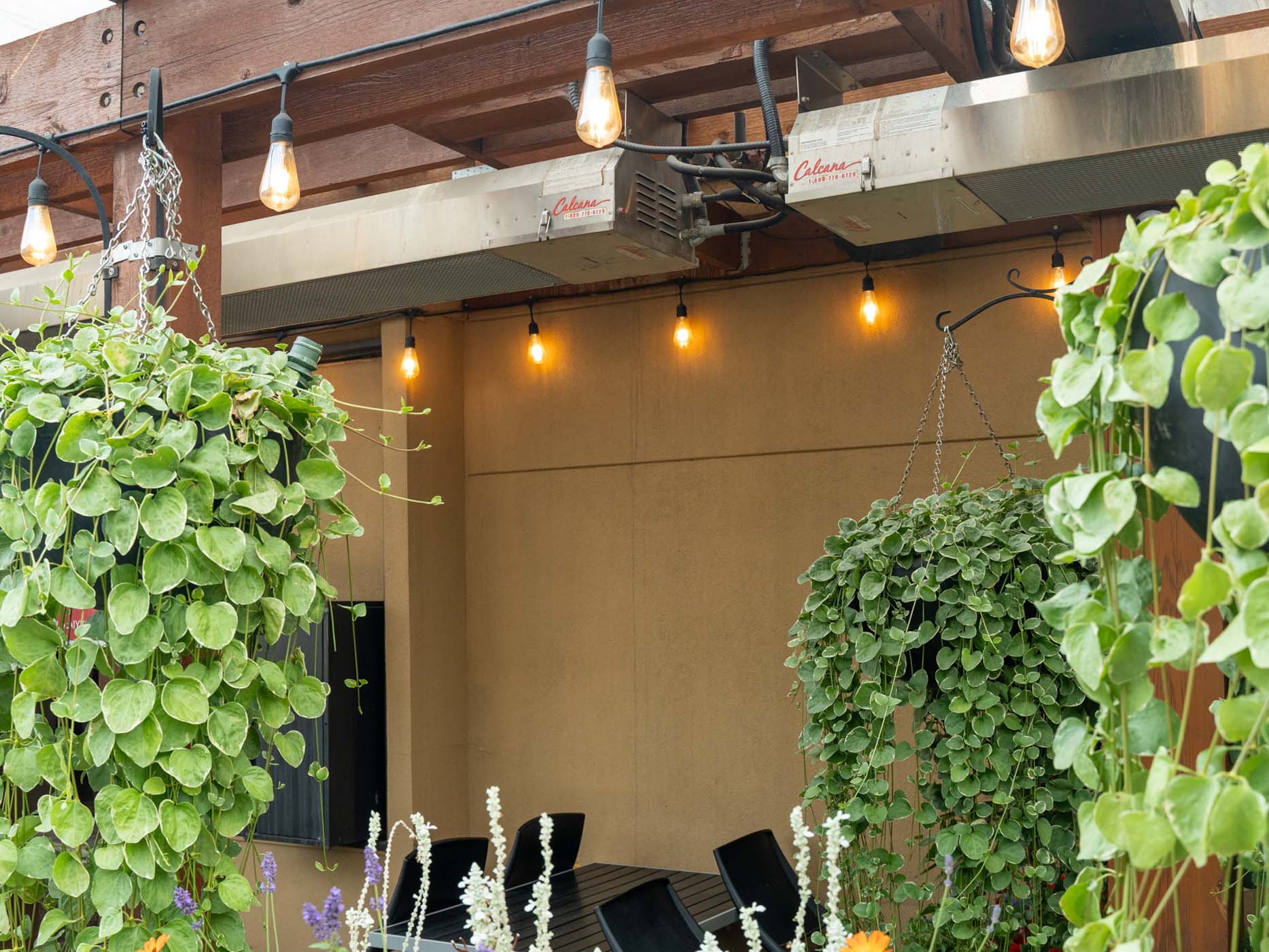 Sleek infrared gas patio heater mounted on a modern backyard pergola, heating a patio lounge area with chairs and plants