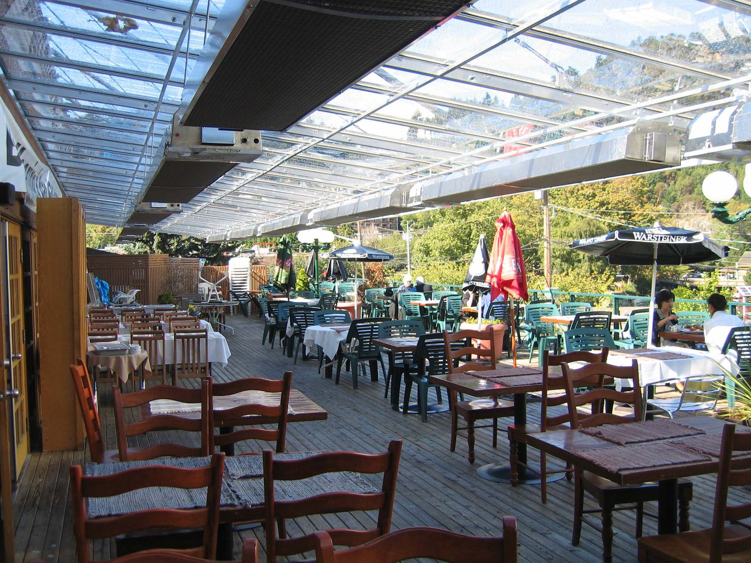 Wall-mounted infrared patio heaters warming an elegant restaurant patio filled with guests dining comfortably in cool weather
